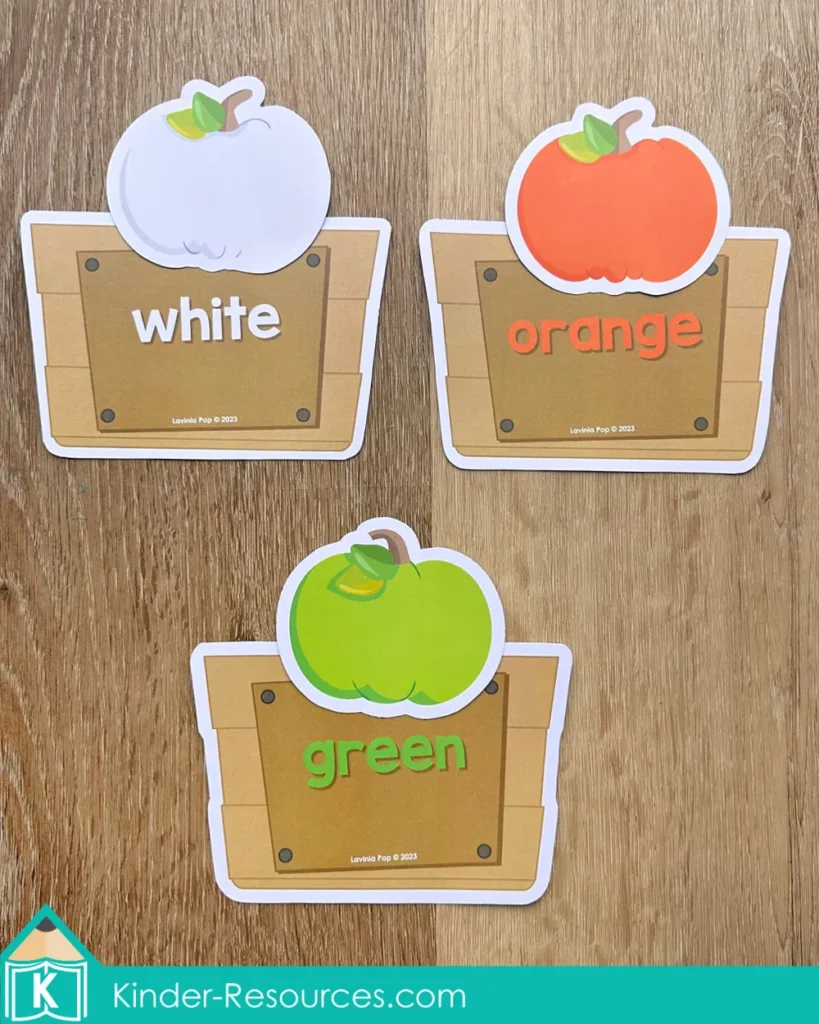Pumpkin color matching crates activity with orange, green, and white pumpkins sorted by color for preschool centers.