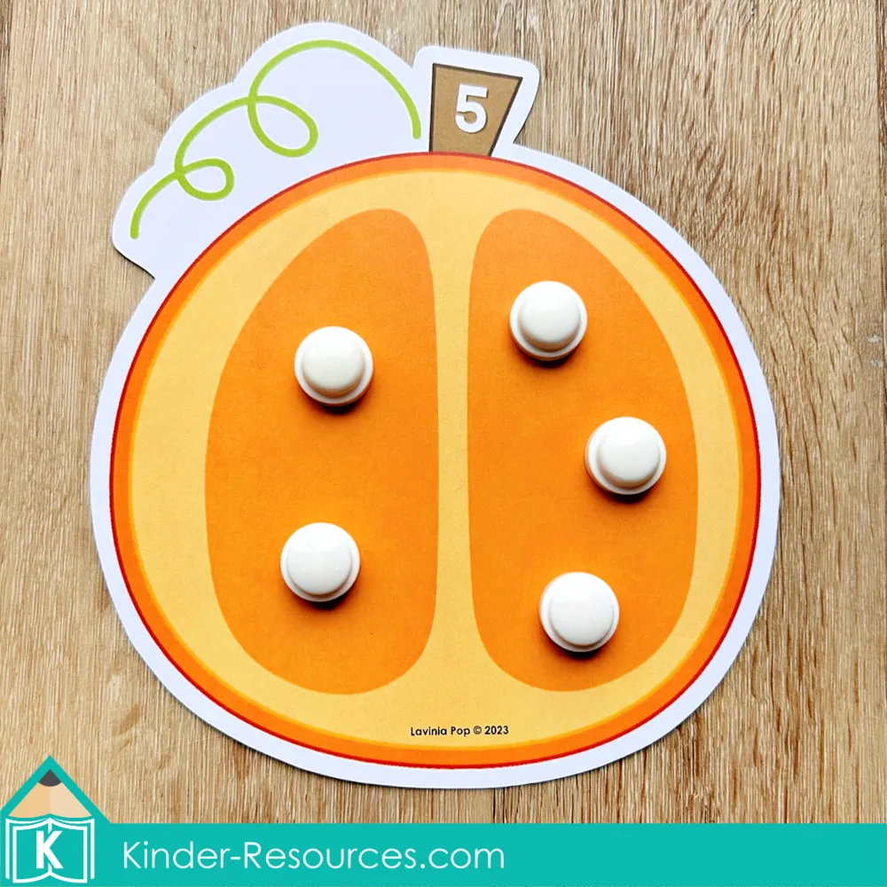 Pumpkin seed counting mat with the number five, using white counters to match the number on the pumpkin.