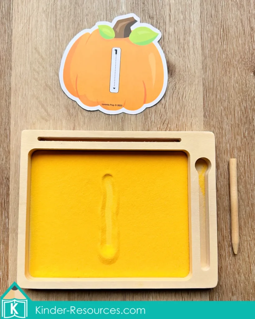 Pumpkin number tracing card with sand writing tray, helping preschool children practice number formation.