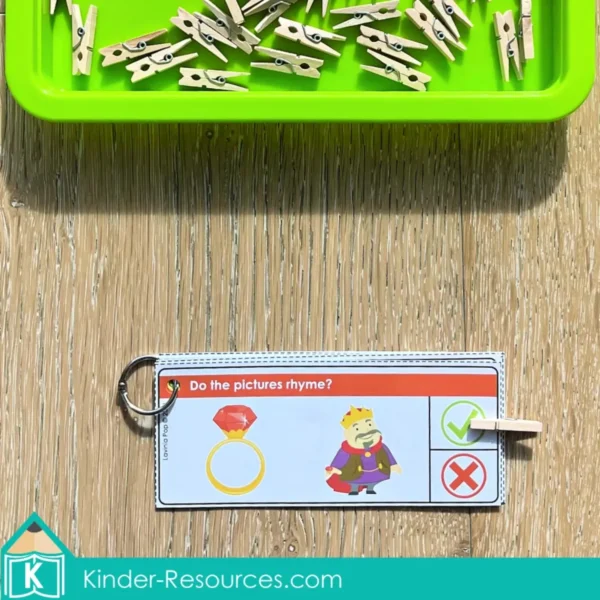 Rhyming task card with ring–king clipped on the check mark using a clothespin. Includes binder ring and mini clothespins for self-checking phonological awareness.