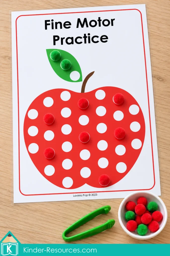 Apple centers for preschool with red and green pom poms covering circles on an apple mat, a supply bowl, and green tweezers.