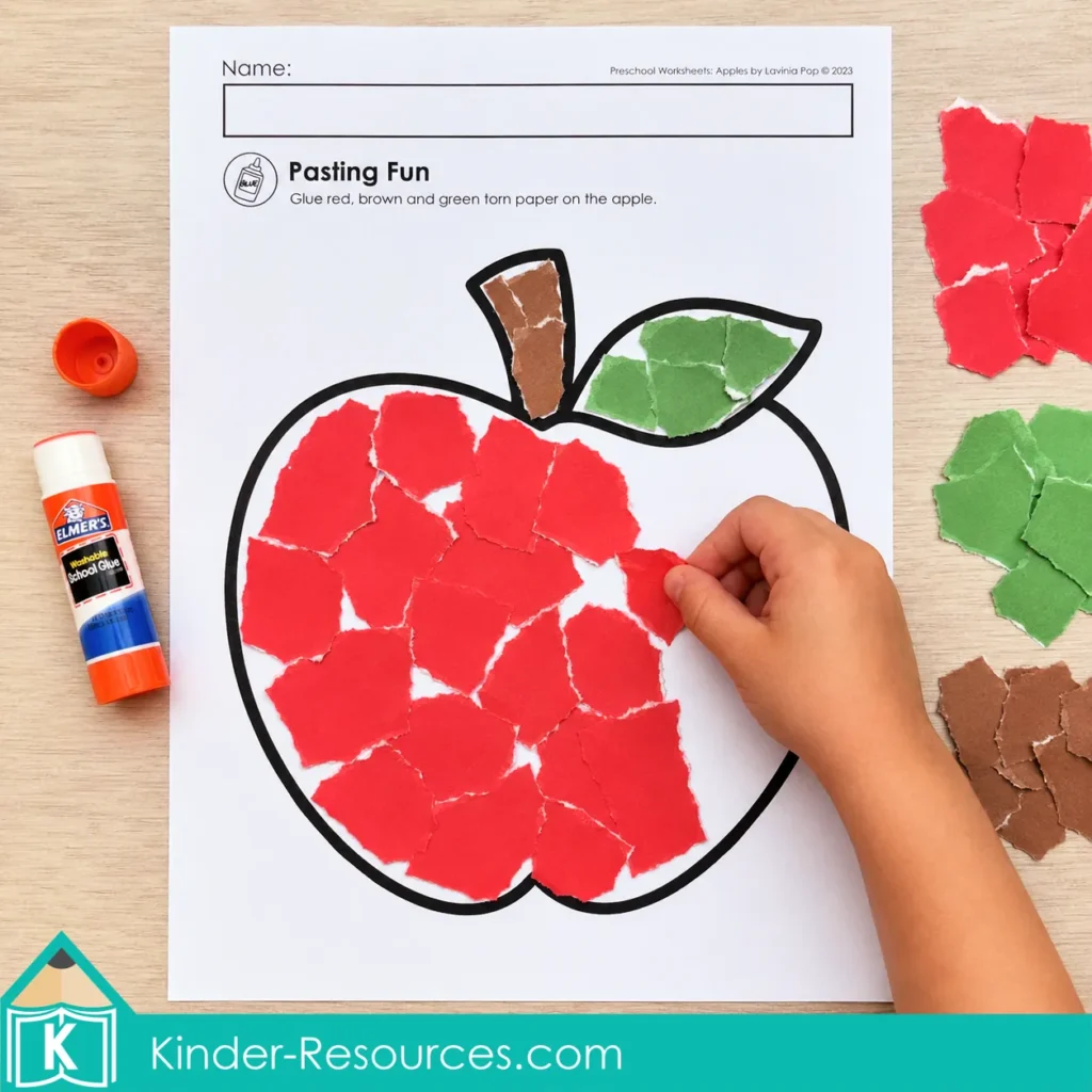 Child completing an apple torn-paper activity with red and green paper and a glue stick.