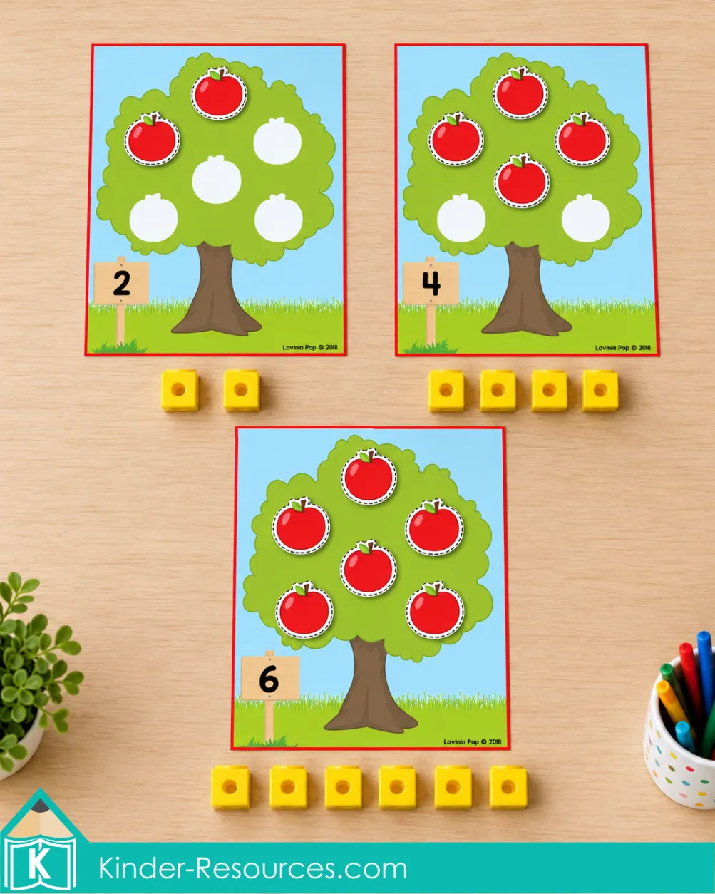 Apple tree mats labeled 2, 4, and 6 with matching quantities of red apples and yellow counting cubes.
