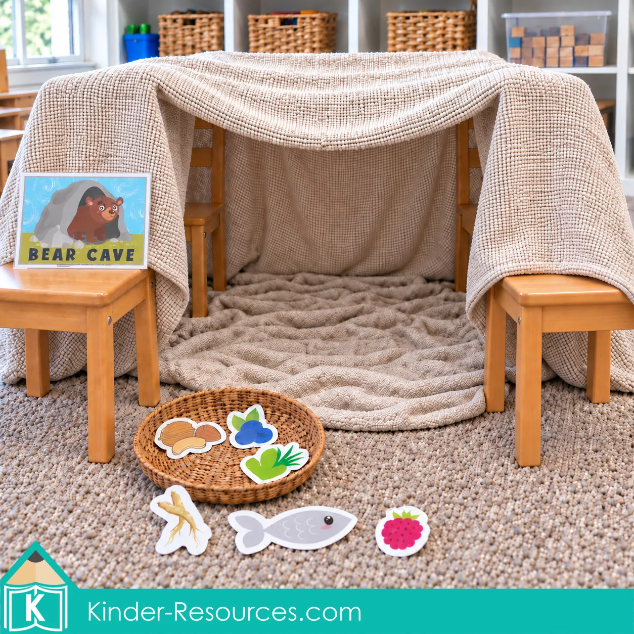 Preschool bear cave made from blankets and wooden chairs, with a printable Bear Cave sign and food cutouts for hibernation pretend play.